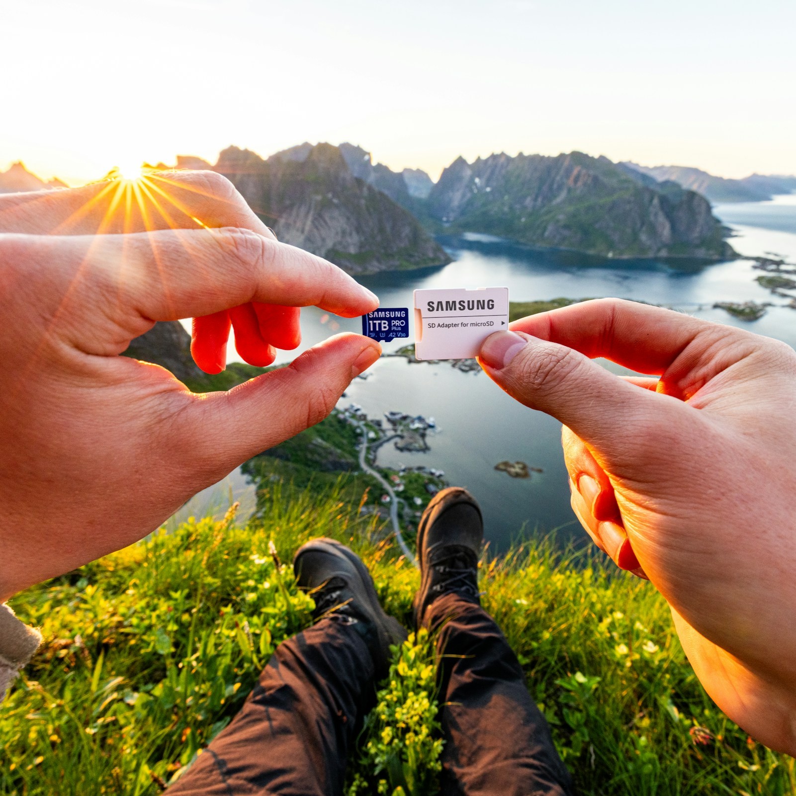 Hands hold sd card against scenic mountain and sea landscape.